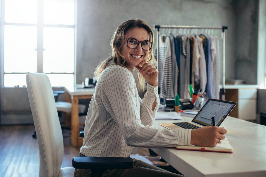 small business owner smiling at her desk and taking down notes