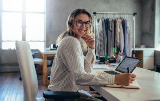 small business owner smiling at her desk and taking down notes